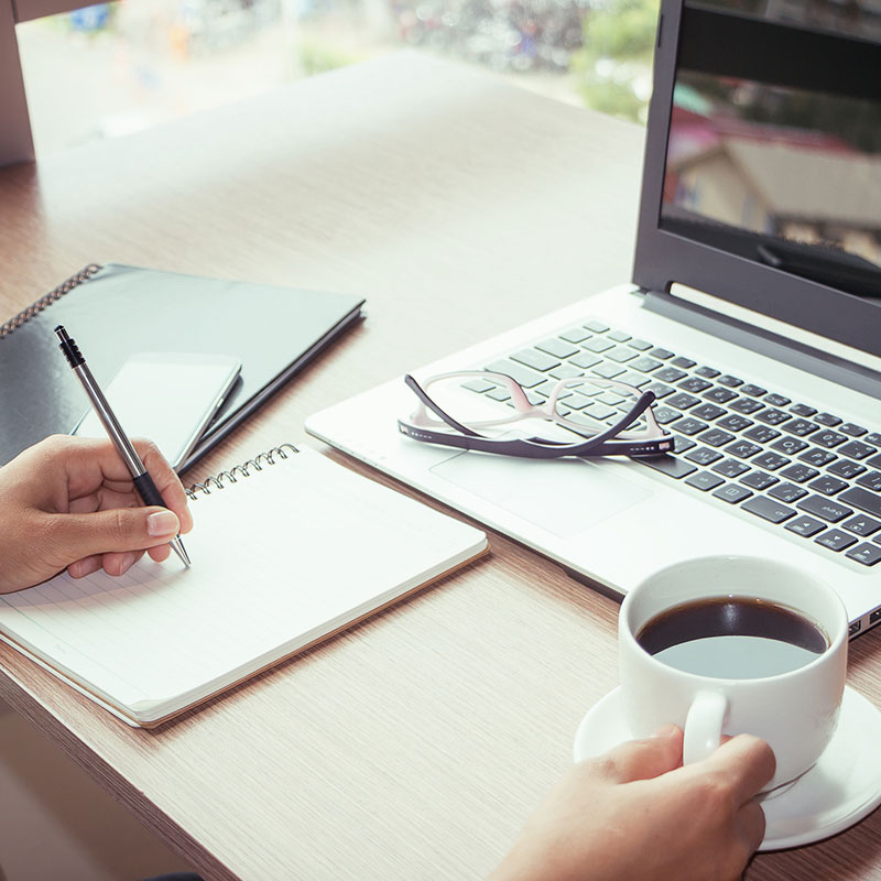 Training Department at Mirjam Quinn & Associates, person at a laptop with coffee and a notebook