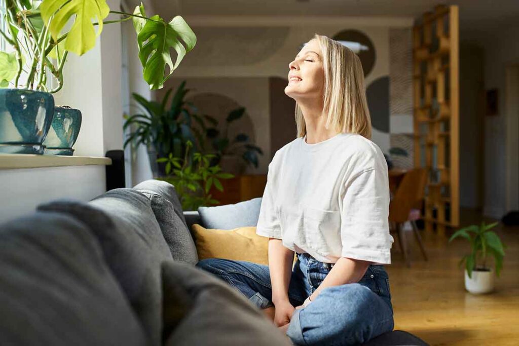 Box breathing tips with Mirjam Quinn & Associates Caitlin Rosswurm, young woman sitting near a window with her eyes closed while she practices box breathing