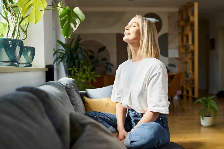 Box breathing tips with Mirjam Quinn & Associates Caitlin Rosswurm, young woman sitting near a window with her eyes closed while she practices box breathing