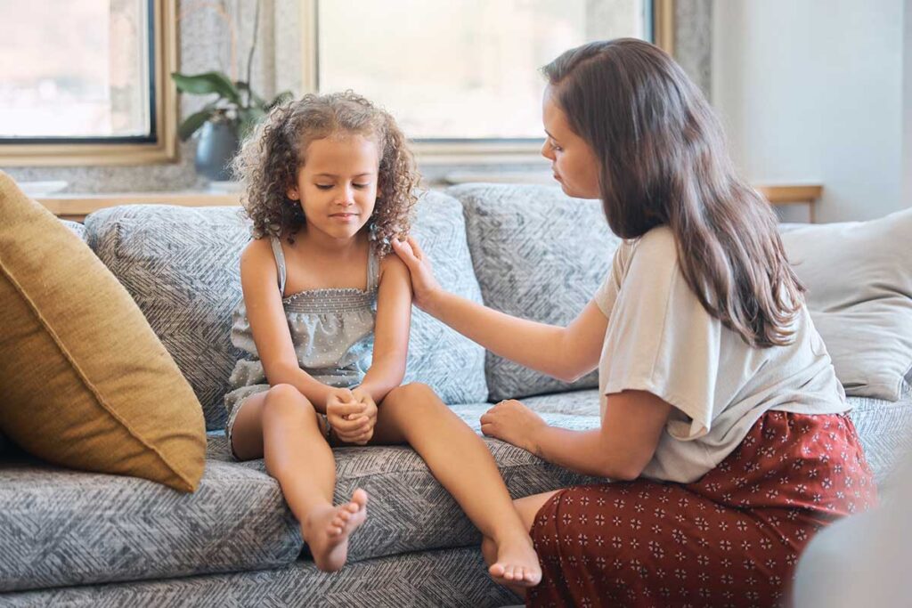 Empathy in children, young girl sad on a coach with a guardian offering support and love